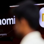 a man walks past a logo of xiaomi, a chinese manufacturer of consumer electronics, outside a shop in mumbai